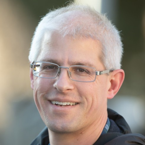 A person wearing glasses and smiling at the camera

Description automatically generated