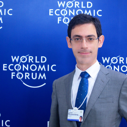 A person wearing a suit and tie holding a sign posing for the camera

Description automatically generated